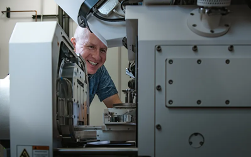 A person smiling while working on the Electron Microscopy Lab (EML) at Los Alamos National Laboratory (LANL)