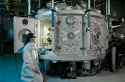 A person in a white lab coat standing next to the Jupiter Laser Facility located at Lawrence Livermore National Laboratory (LLNL)